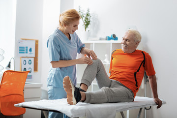 Pleasant senior man having a knee massage