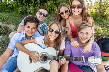 group of teenagers spending time together with guitar