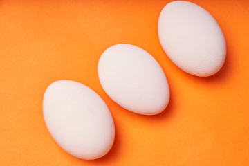 Chicken eggs laid out on an orange background