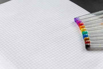 Bunte Farbstifte mit Glitzer liegen bereit auf einem karierten Blatt Papier für Malen, Zeichnen...