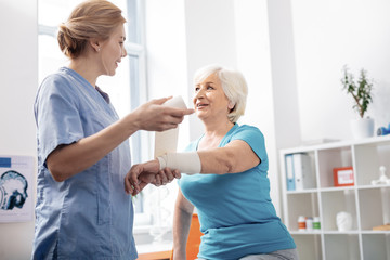 Pleasant delighted nurse holding a white bandage