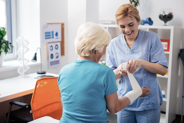 Delighted blonde woman talking with her aged patient