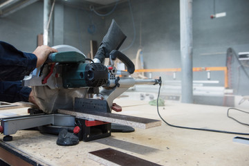 Furniture production or craft concept: worker making the wood surface of furniture part with special machine