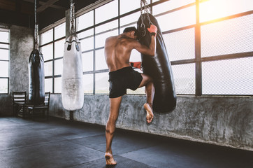 Muay thai fighter training in gym with punching bag - obrazy, fototapety, plakaty