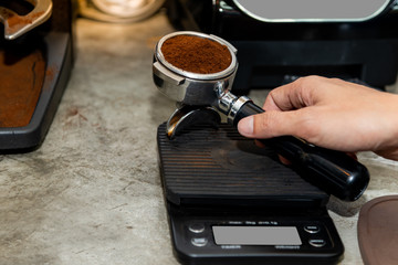 The coffee maker is weighing the roasted coffee that has been crushed in order to obtain the base according to the recipe, to coffee barista concept.