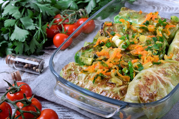 Raw cabbage rolls with fried vegetables in a glass dish ready to be roasted