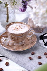 Freshly brewed coffee with a milky foam topped with cinnamon in a brown cup