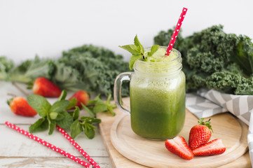 Glass jar with green smoothie with kale leaves, mint and strawberry. Detox drink. Healthy cocktail