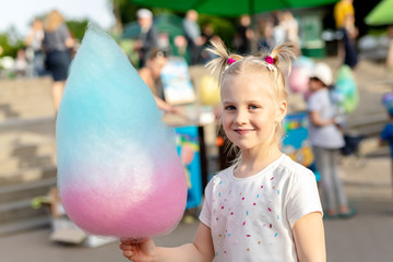 Cute little caucasian blond kid girl holding in hand stick with Bright big multicolored cotton...
