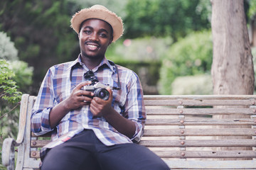 African Man Traveler holding camera with green natural background