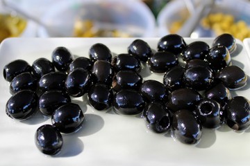 Small white plate with black olives