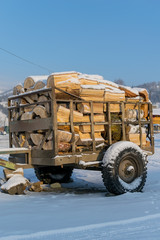 Obraz premium Cart, trailer, wagon for transportation of firewood is for sale in the countryside in the snow in winter
