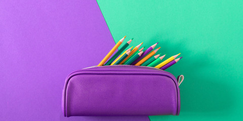 Back to school. Colorful minimal composition of school supplies on green and purple background....