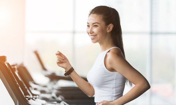 Cardio training. Asian woman running on treadmill in gym