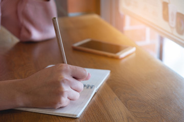 Business woman hands with pencli writing on notebook, desk of brown