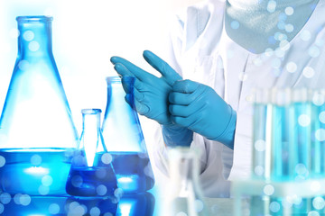 Scientist putting on protective gloves in laboratory, closeup. Solution chemistry