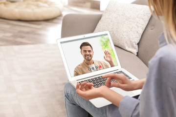 Young woman using video chat on laptop in living room, closeup. Space for design