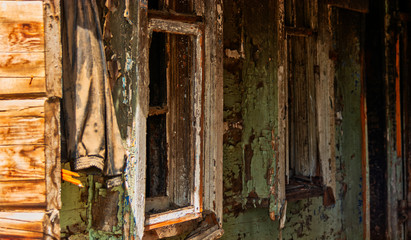 Windows in row of house made of wood half demolished