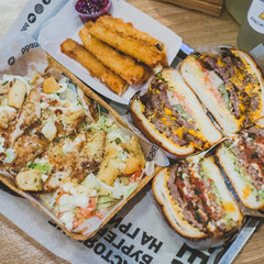Close-up sliced meat burgers, Caesar salad and cheese sticks lie on a tray in a cafe. There are illegible inscriptions on the package.