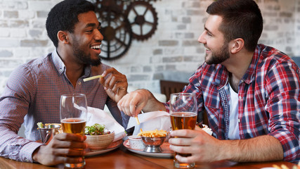 Friends Resting In Bar, Drinking Beer And Eating French Fries