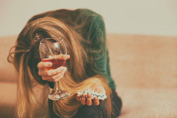 Depressed woman drinking  alcohol while sitting alone at sofa.Toned image.