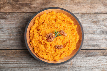 Bowl with mashed sweet potatoes on wooden table, top view