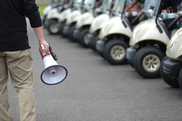 A gentleman holds a megaphone just prior to briefing golfer participating in a golf outing.