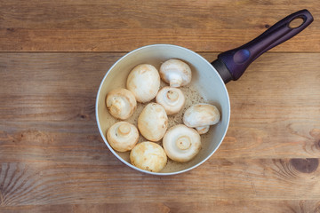Bowl of fresh champignon mushrooms on wooden background