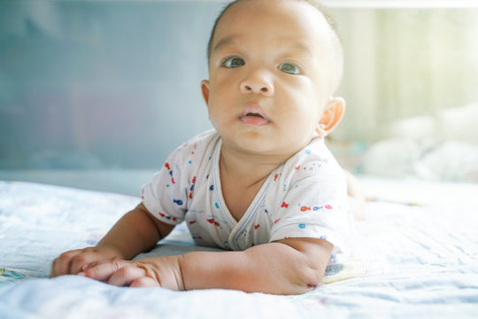 Funny baby boy crawling on blanket in bed room