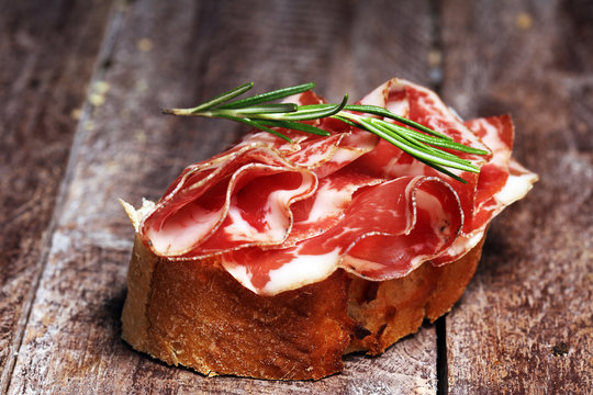 Italian sliced cured coppa with spices. Raw ham. Crudo or jamon with rosemary