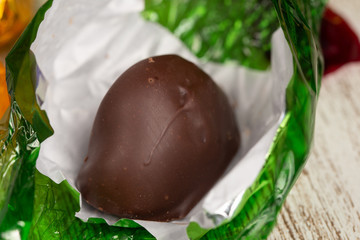 Close up view of an unwrapped chocolate on a green cellophane paper