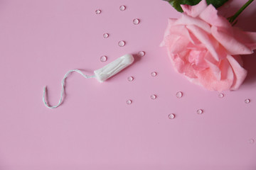 Clean white cotton tampon on pink background with drops. Isolated. Copy space. Menstruation. Feminine Hygiene in periods, beauty treatment. Flat lay.