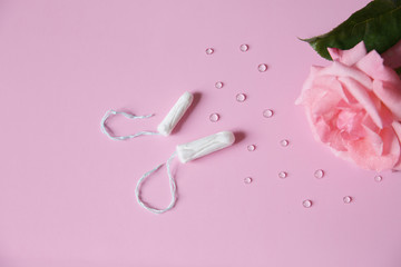 Obraz na płótnie Canvas Two clean white cotton tampons on pink background with drops. Isolated. Copy space for text. Menstruation. Feminine Hygiene in periods, beauty treatment. Flat lay. Top view.