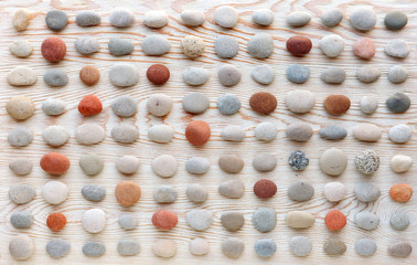 pattern of colored pebbles on white wooden background. Flat lay, top view