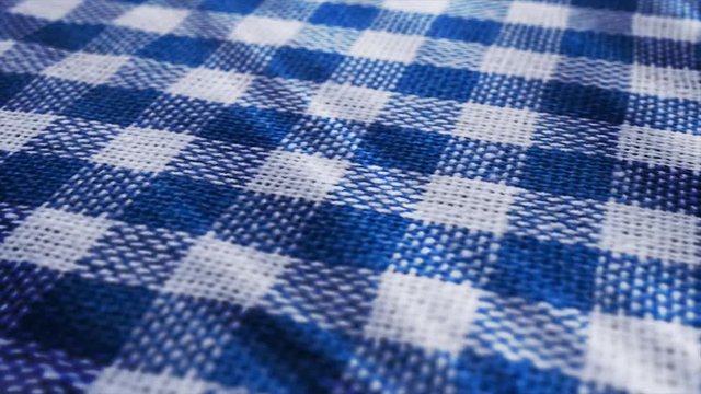 Blue white tablecloth, picnic gingham is waving. Close up macro shot checkered fabric cloth background.