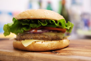 Closeup of home made beef burger with lettuce and mayonnaise served on little wooden cutting board.
