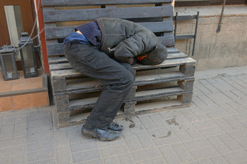 homeless asleep on the bench at the entrance to the store