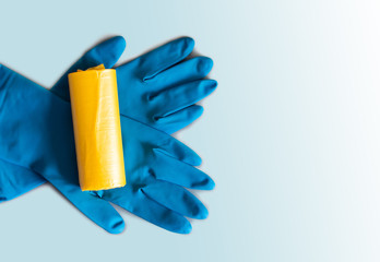 Roll of yellow trash bags and blue rubber gloves.