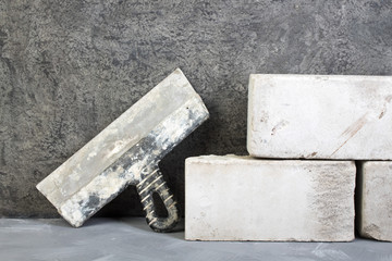 silicate bricks, putty knife on the gray concrete background. Copy space. Top view.