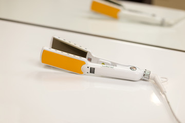 Curling tongs with ceramic plates on a white table