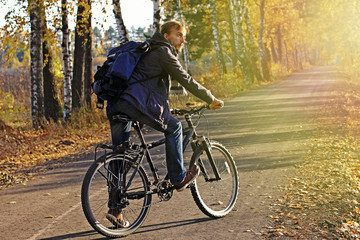 Fototapeta na wymiar Bearded hipster man in casual wear with backpack and bicycle in autumn park or forest on sunset. Discovery beautiful fall season