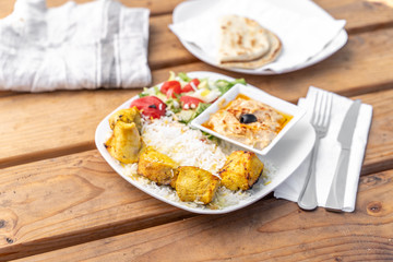 Greek chicken platter with rice and hummus served in a Mediterranean restaurant.