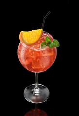 Big round wine glass with fresh cold red cocktail isolated on black background