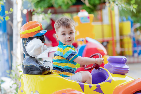 Child riding toy car. Little boy playing with big bus. Kid driving plastic truck in indoor playground or kindergarten. Toddler at day care play room. Toys for little boys. Daycare amusement center.