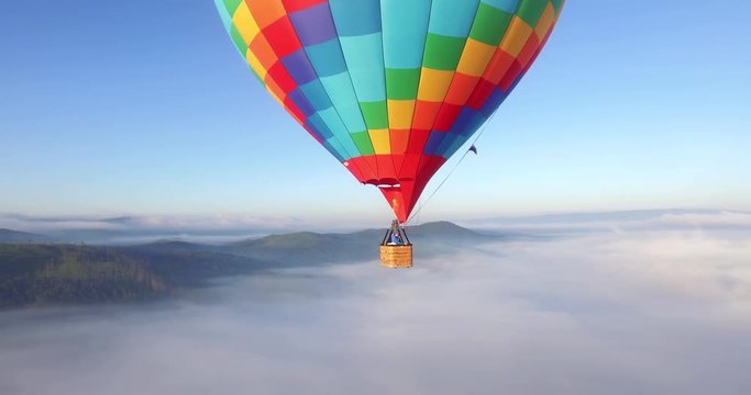 Colorful hot air balloon epic flying above mountain over the fog at sunrise