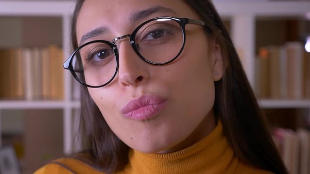 Close-up portrait of stylish brunette teacher posing smilingly into camera at the library.