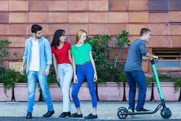 Obraz premium Jugendliche schauen E-Scooter-Fahrer nach