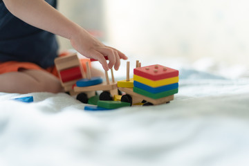 Growing up and kids leisure concept. A child playing with a colored wooden train. Kid builds constructor. Without face. Selective focus, copy space, mocup