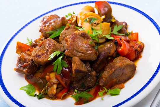Cooked fried pork meat with peppers, mushrooms  and greens