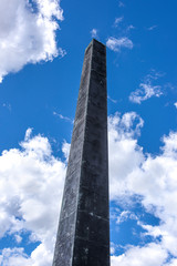 Germany, Bavaria, Munich, Karolinenplatz: Famous obelisk - total height 29 meter - from below in the city center of the Bavarian capital with cloudy blue sky in the background - concept history